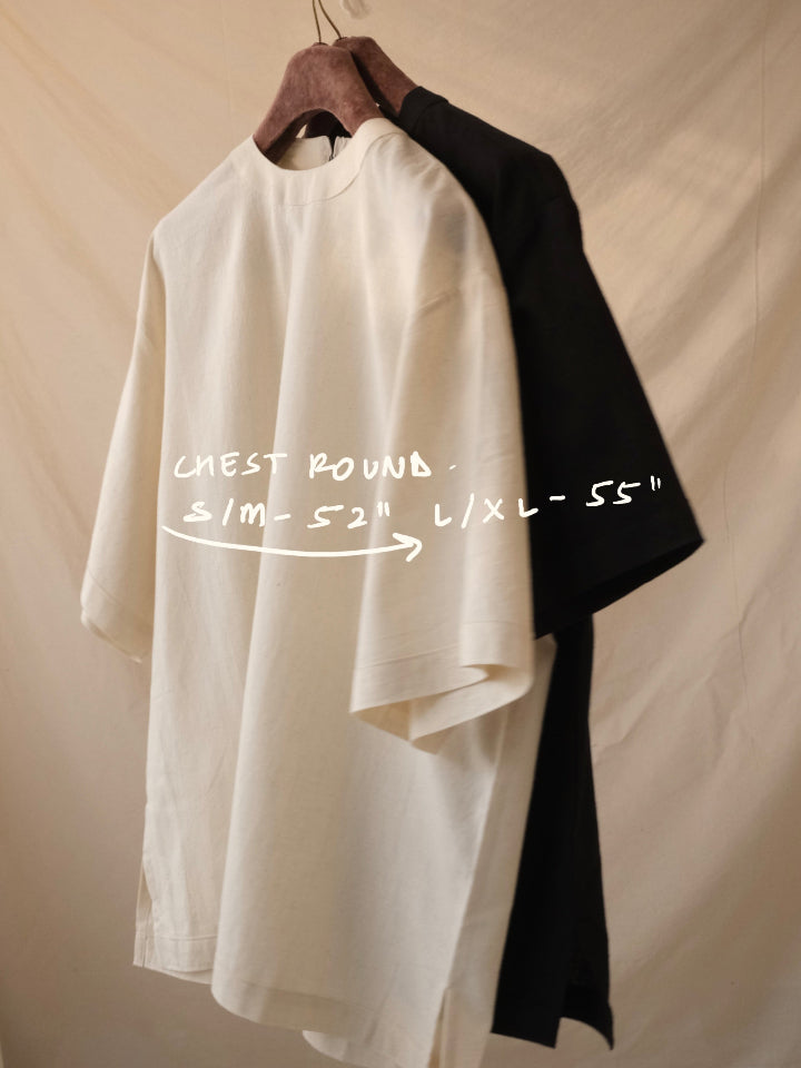 White shirt on a hanger with black sleeve, measurement text overlay on a beige background