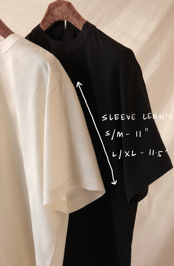 Black and white t-shirts with sleeve length measurement labels on a beige background